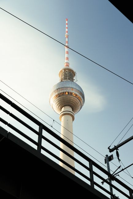 Berlin TV Tower framed by railway tracks on a clear day.