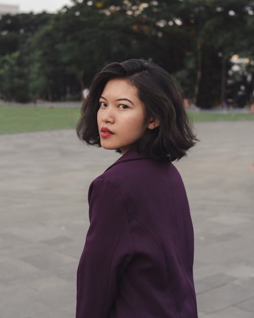 Woman in Purple Long Sleeve Blazer Standing on Gray Pavement