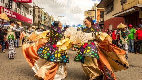 Free Vibrant street festival with dancers in traditional attire showcasing Filipino culture. Stock Photo