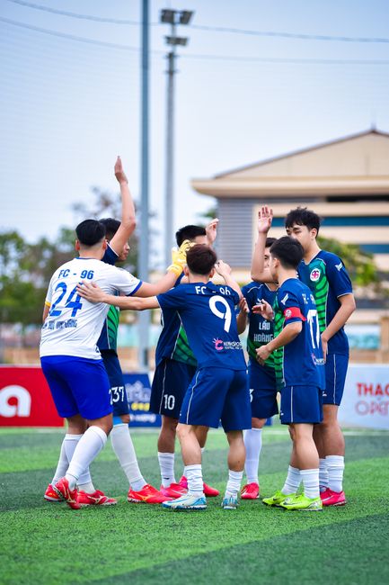 A team of young soccer players huddle on a field in Hà Nội, Vietnam, ready for a match.