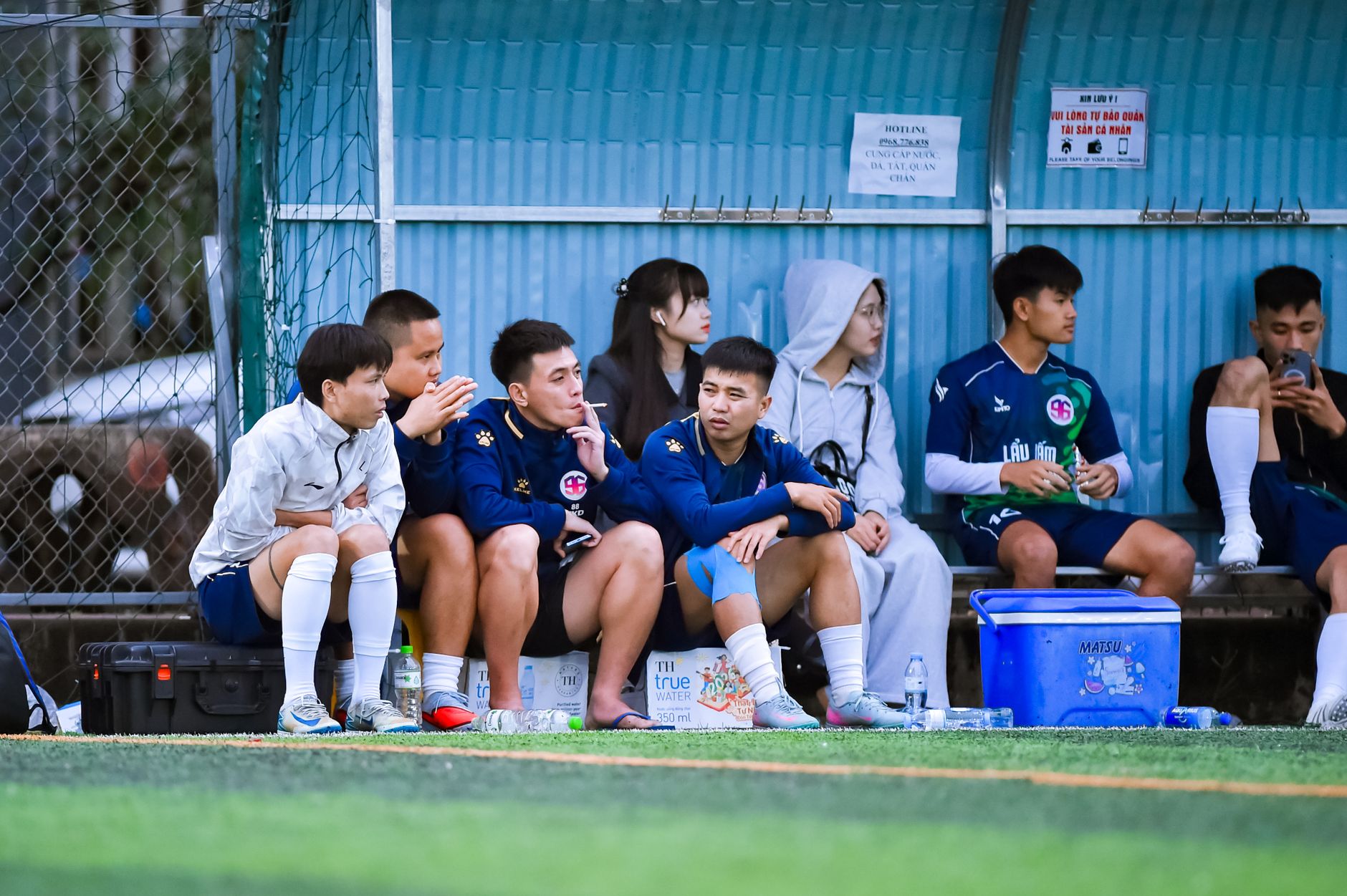 Football players waiting outside the penalty area while the referee reviews a replay on the pitch monitor