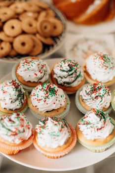 Delicious vanilla cupcakes topped with colorful holiday sprinkles, perfect for festive celebrations.