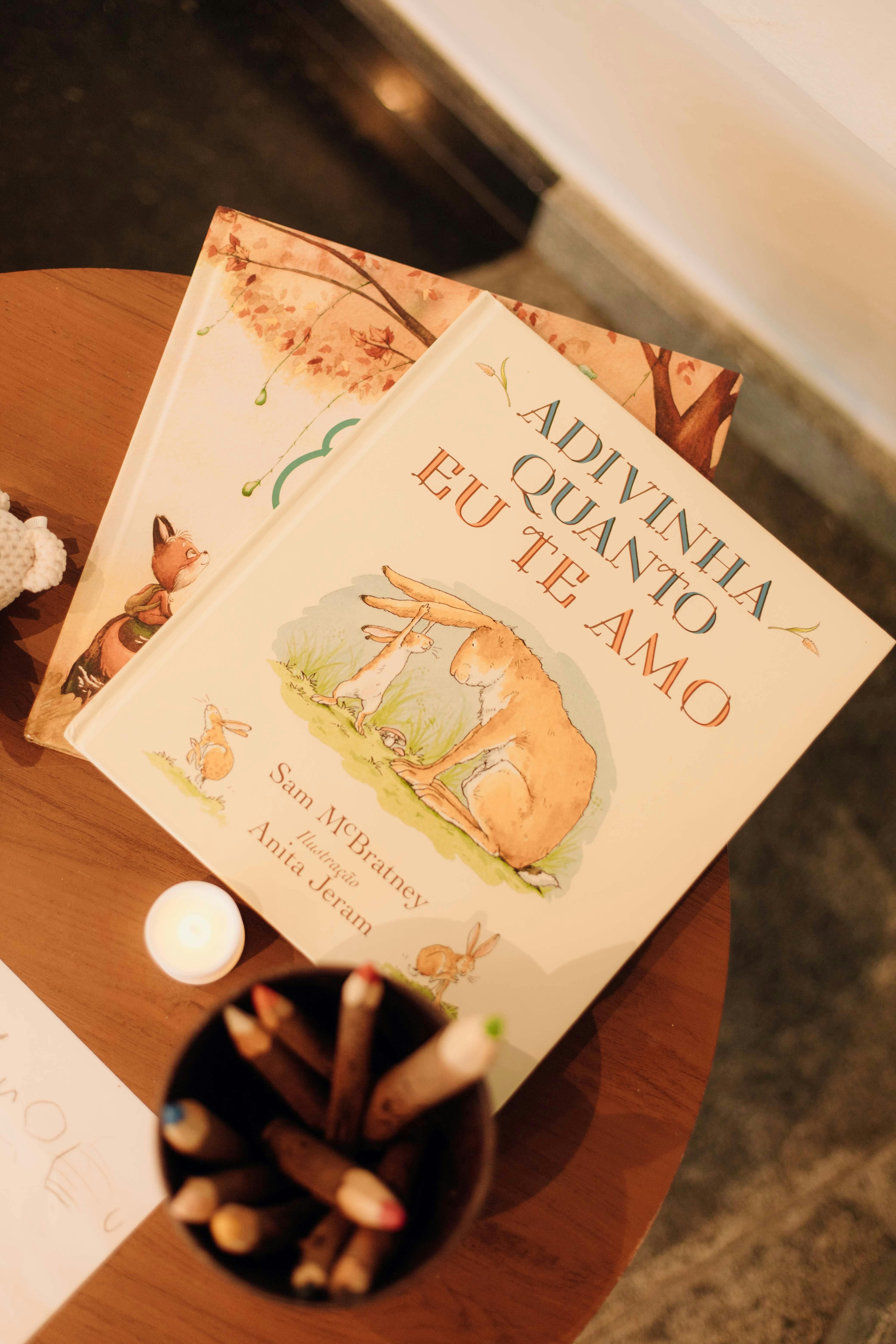 A warm and cozy scene featuring children's books on a wooden table, lit by candlelight.