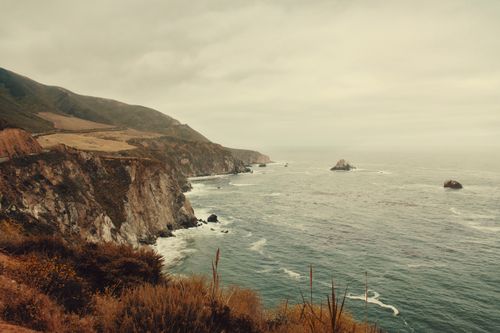 Free Stunning view of dramatic coastal cliffs meeting the ocean's waves under a cloudy sky. Stock Photo
