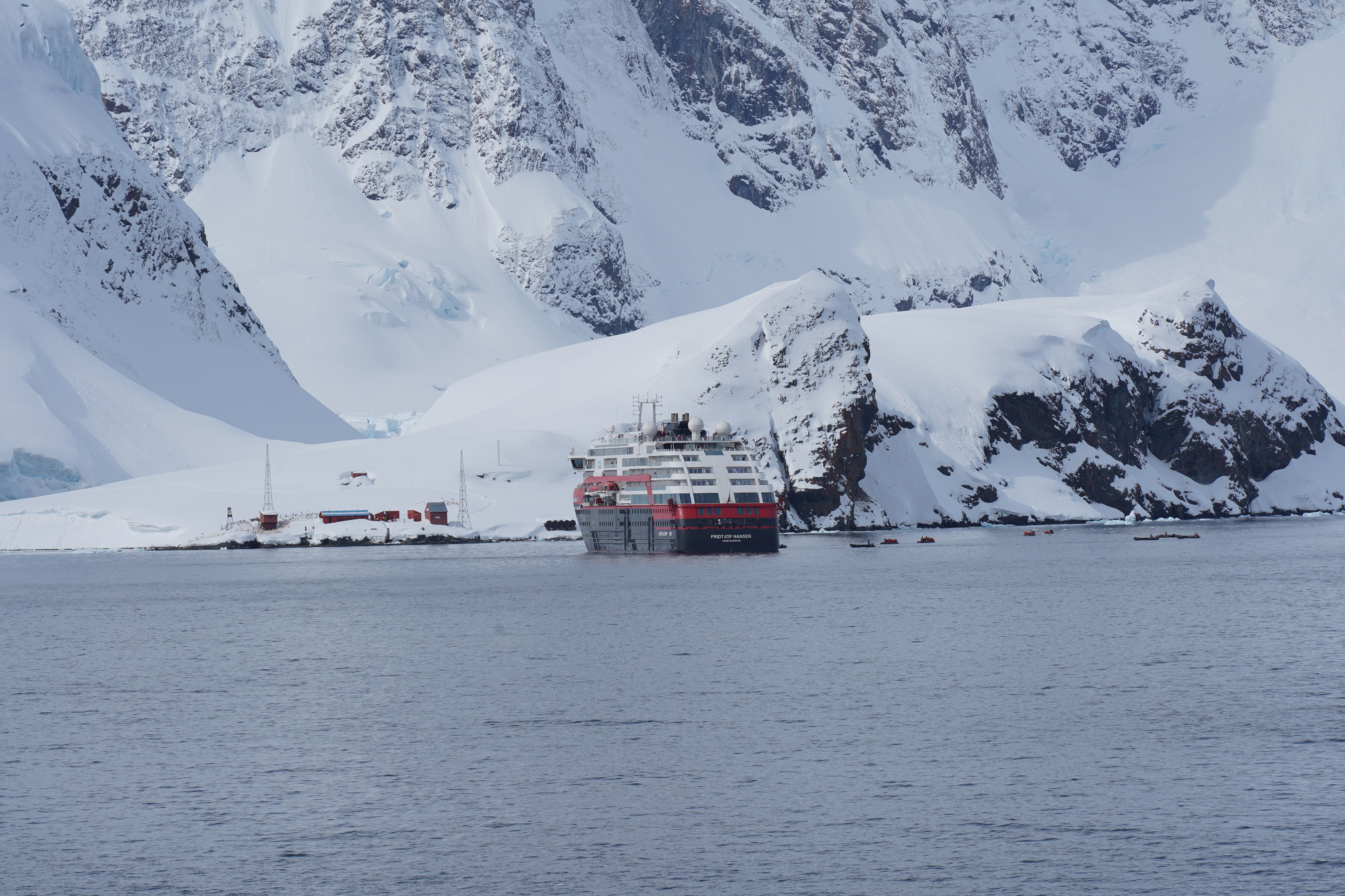 A cruise ship navigating through icy waters surrounded by majestic Antarctic icebergs.