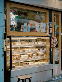 Inviting cake shop display with various pastries and an open sign, perfect for dessert lovers.