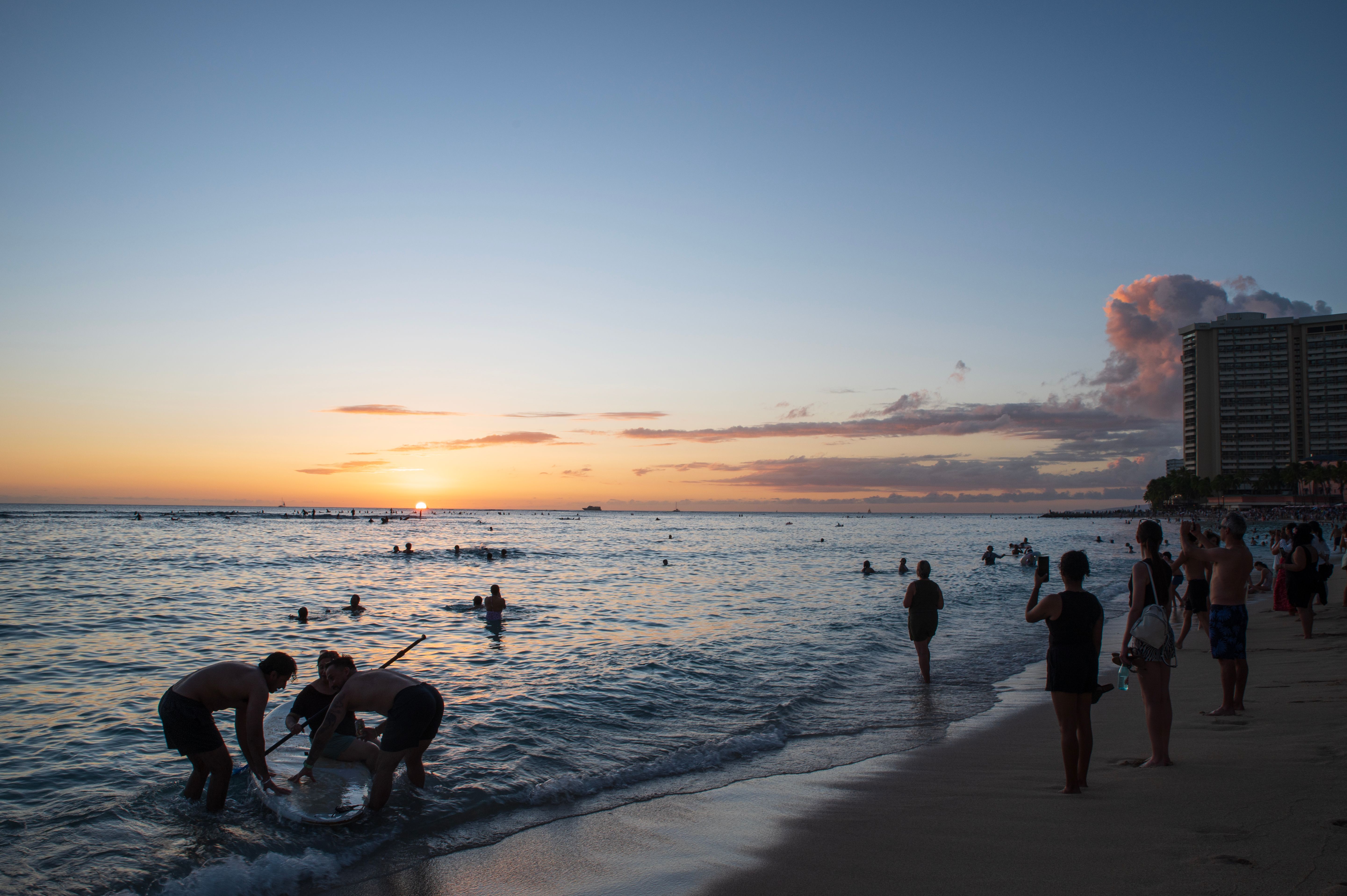 Sunset Beach Scene with People Enjoying Water · Free Stock Photo