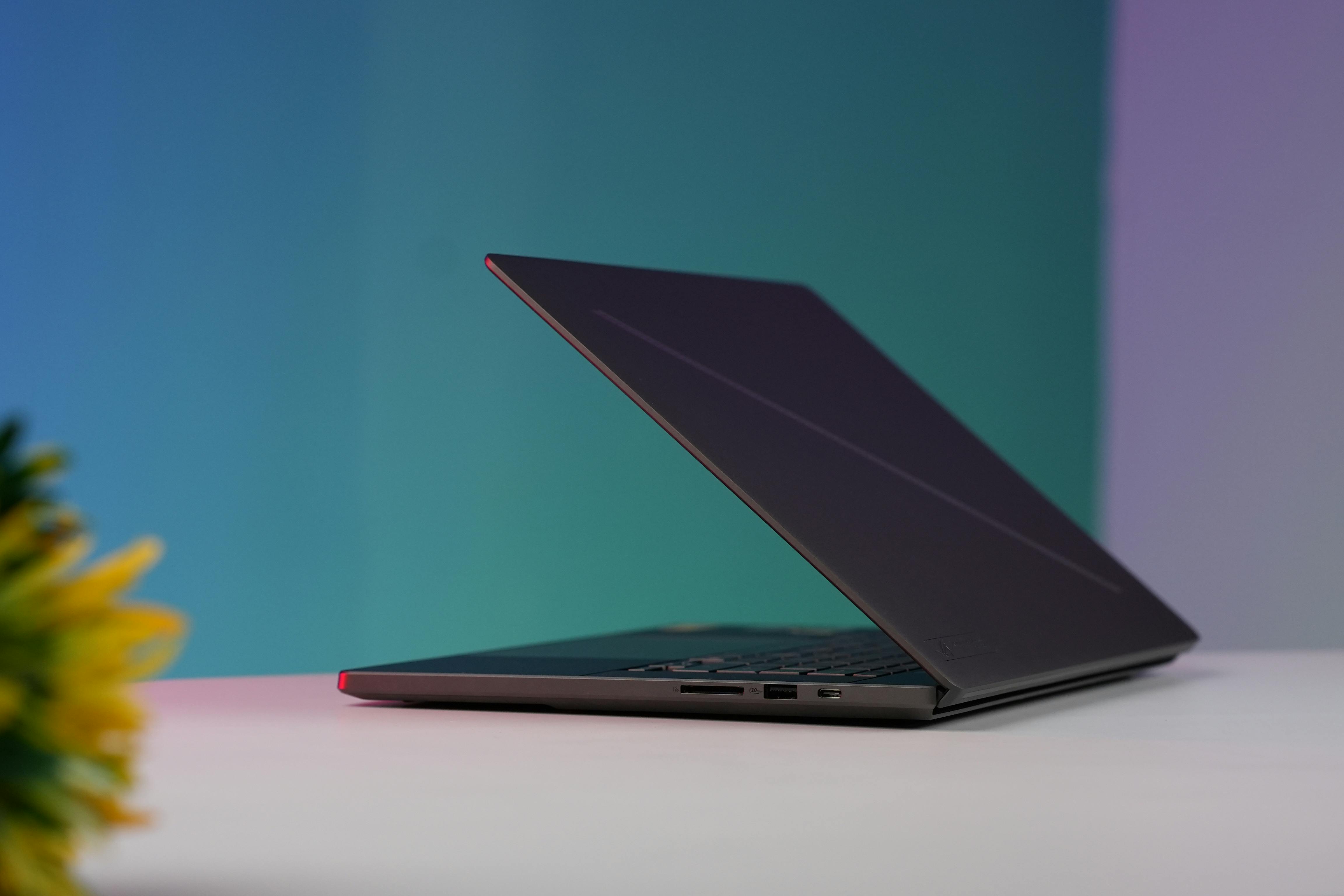 Side view of a sleek laptop on a desk, illuminated by a colorful gradient background.