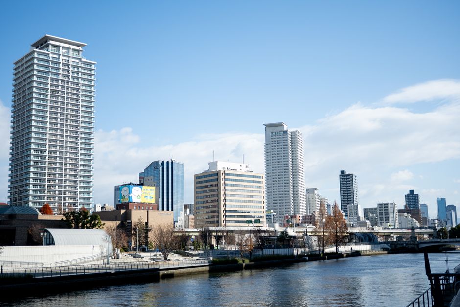 A vibrant urban skyline along a river in Osaka, Japan showcasing modern architecture.