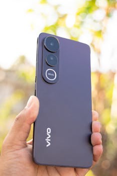 A sleek smartphone held in a hand against a blurred outdoor background, capturing modern technology.