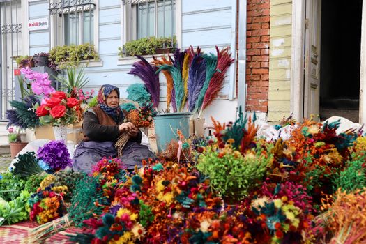Vibrant flower market scene with a woman arranging colorful bouquets outdoors.