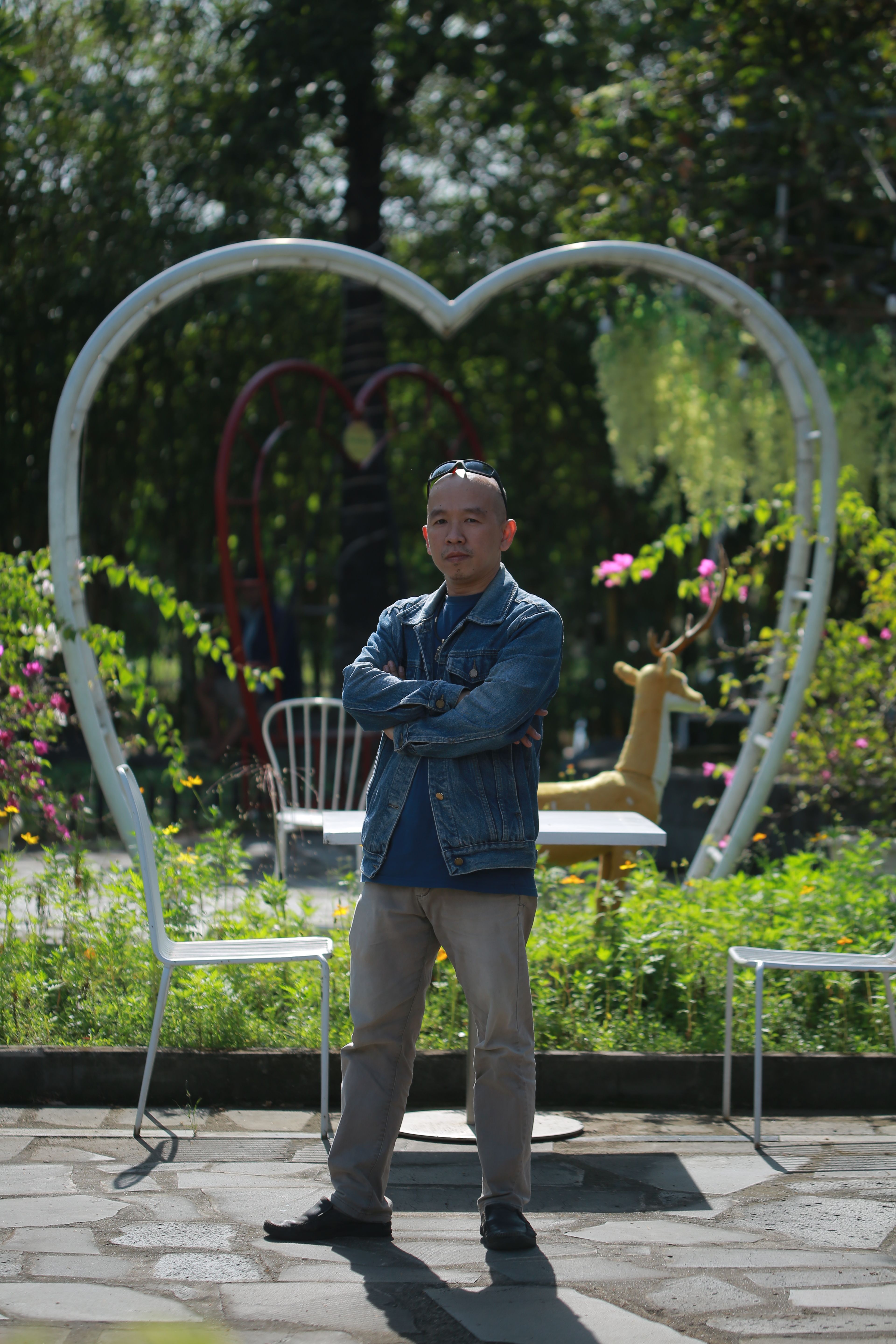 Man poses confidently in an artistic heart-shaped garden setting.