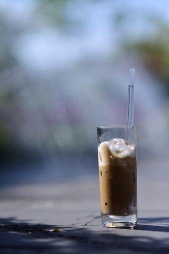 Tall glass of iced coffee with a straw on a sunlit street table, photo by S&oacute;c Năng Động on Pexels