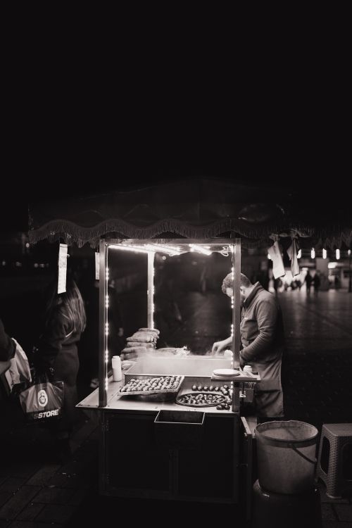 Free Atmospheric black and white photo of a street vendor at night under soft lights. Stock Photo