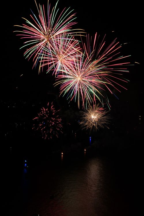 Free Colorful fireworks explode over water in a dazzling night sky display. Stock Photo