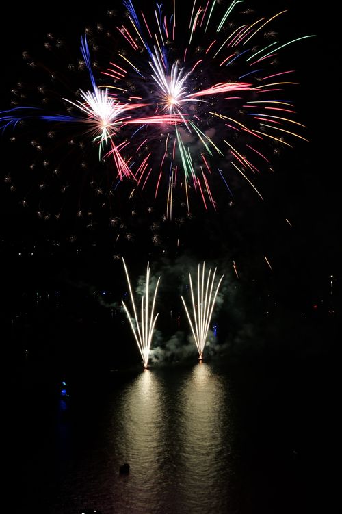 Free Colorful fireworks lighting up the night sky above a tranquil water surface. Stock Photo