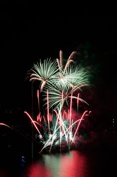 A spectacular fireworks display illuminating the night sky over a body of water, casting colorful reflections.