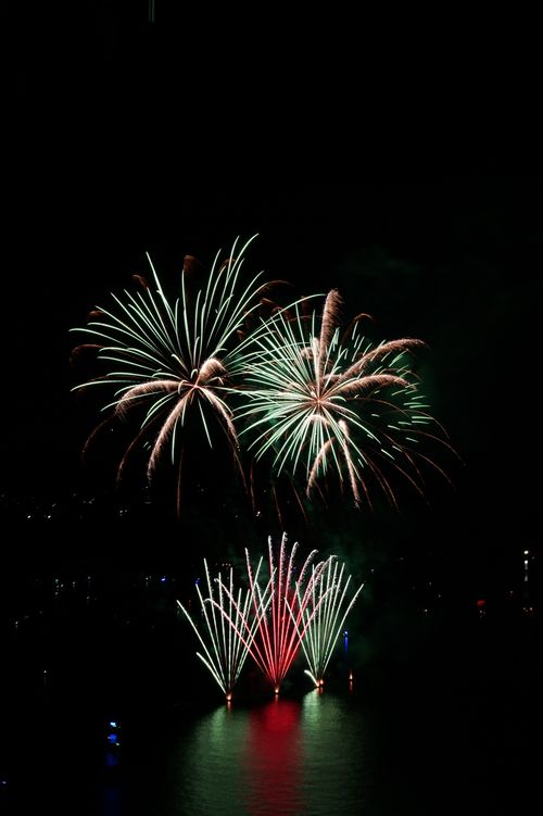 Free Vibrant fireworks lighting up the night sky over a body of water, creating a festive atmosphere. Stock Photo