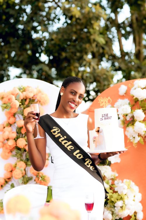 Free Smiling bride-to-be holding a cake and wine glass at her celebration in Kigali, Rwanda. Stock Photo