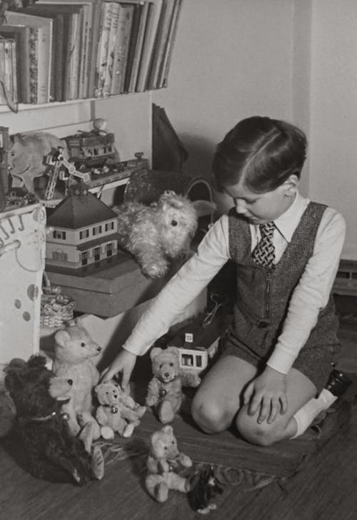 бесплатная Фотография малыша, играющего в игрушки с медведем в оттенках серого Стоковое фото