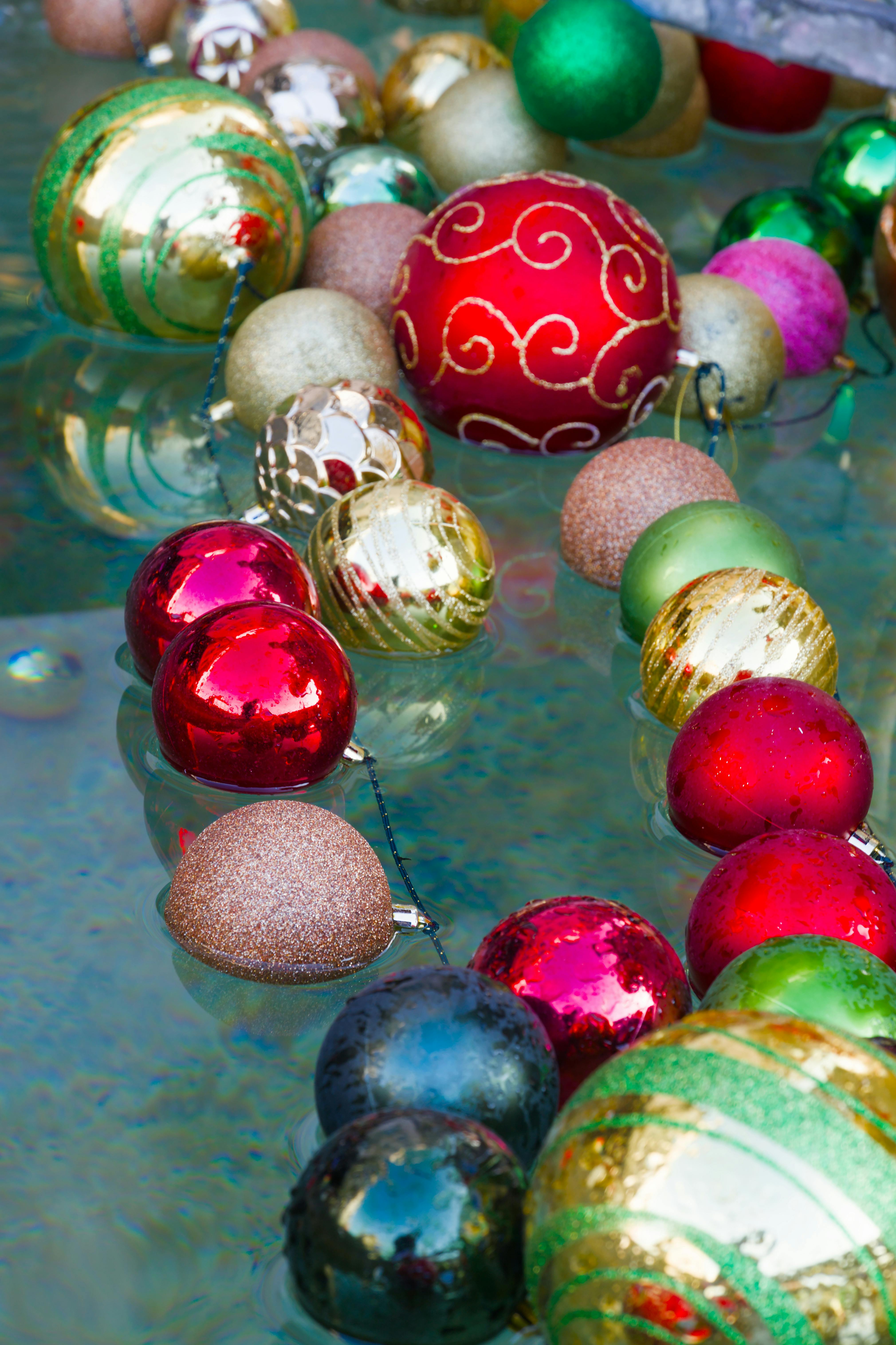 Colorful Christmas baubles floating gracefully on water, evoking festive cheer.