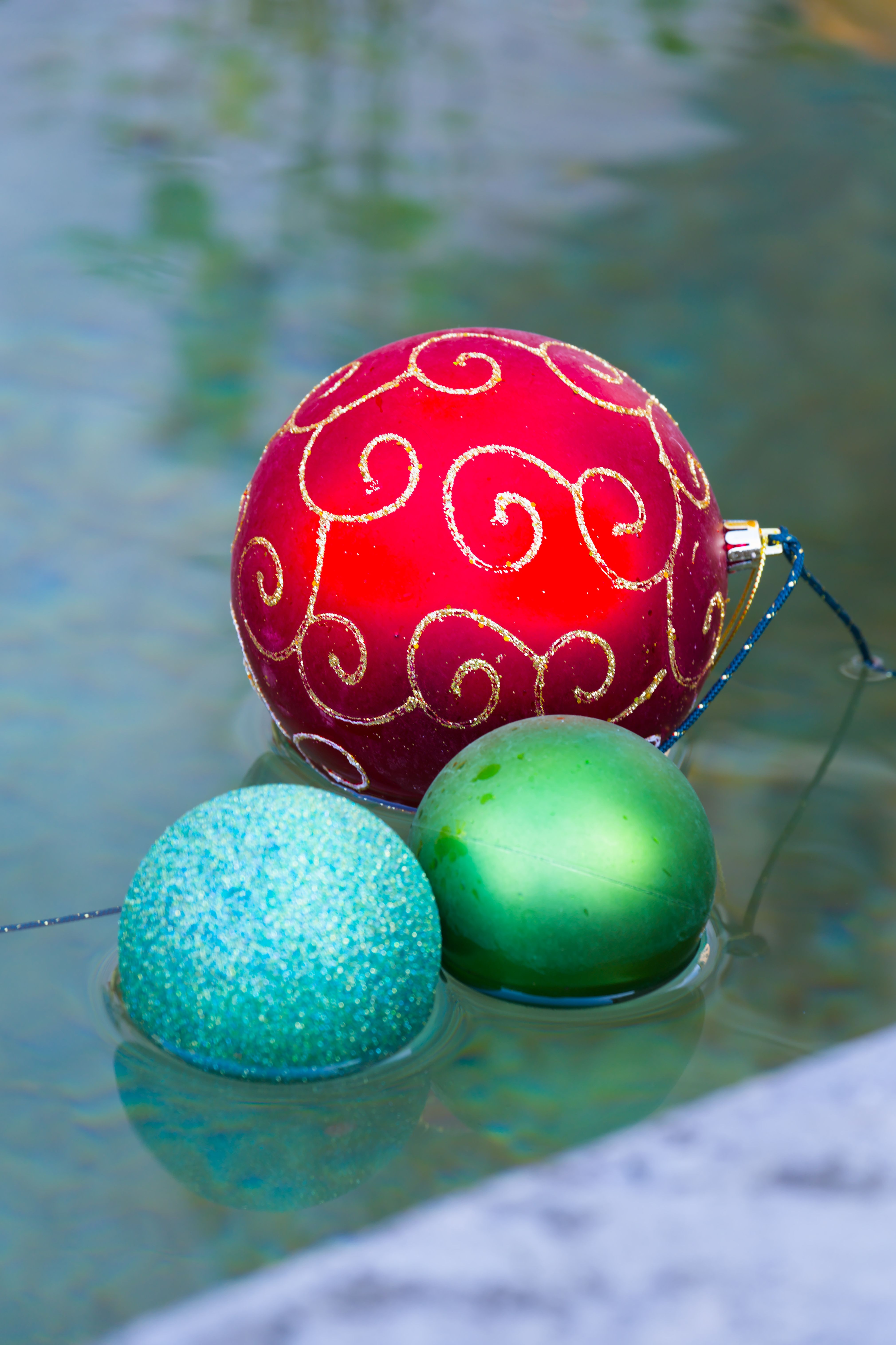 Red, green, and blue Christmas ornaments floating in water, creating a festive and vibrant holiday scene