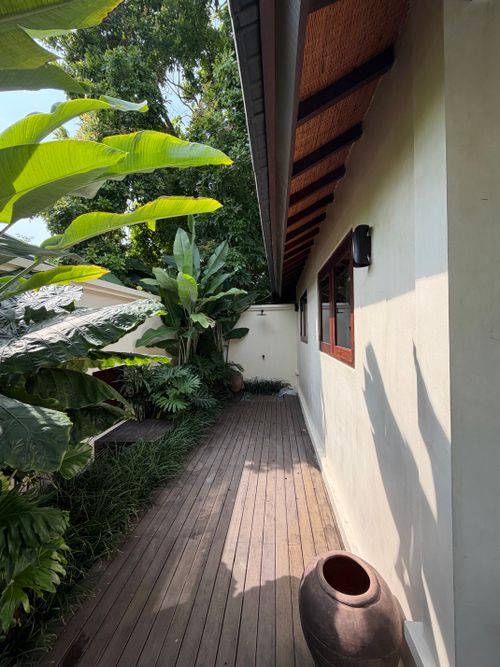 Free A serene wooden deck surrounded by tropical plants, ideal for relaxation. Stock Photo