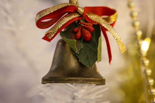 Free Close-up of a Christmas bell decoration adorned with a red bow, perfect for holiday ambiance. Stock Photo