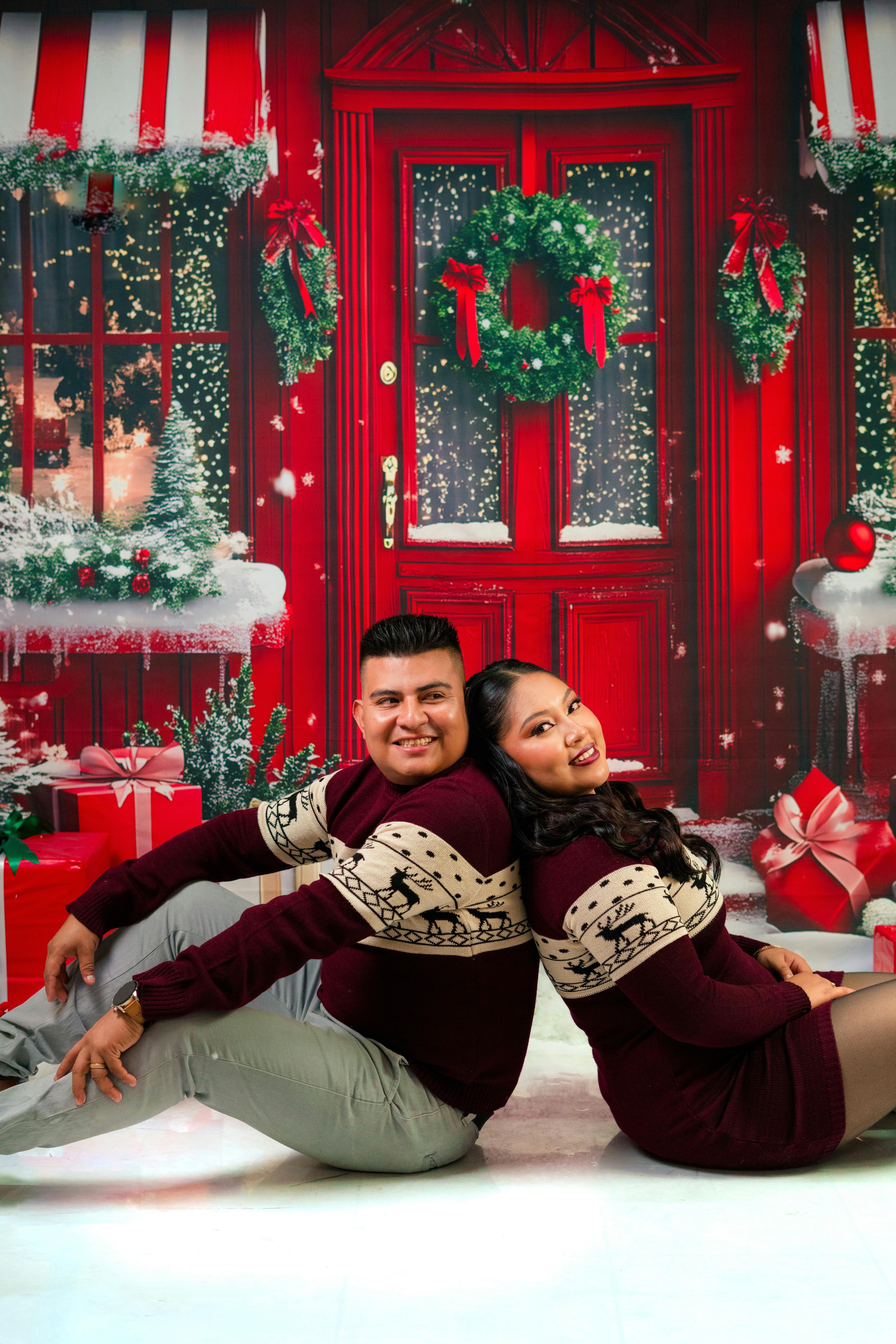 Happy couple posing with Christmas backdrop and gifts.