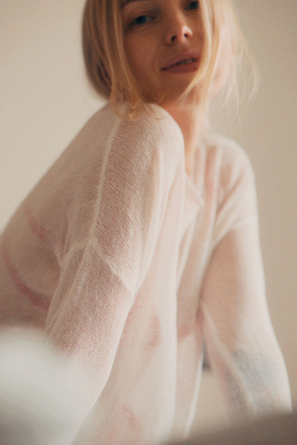 A soft-focus portrait of a woman in fine knitwear — the refined summer knit