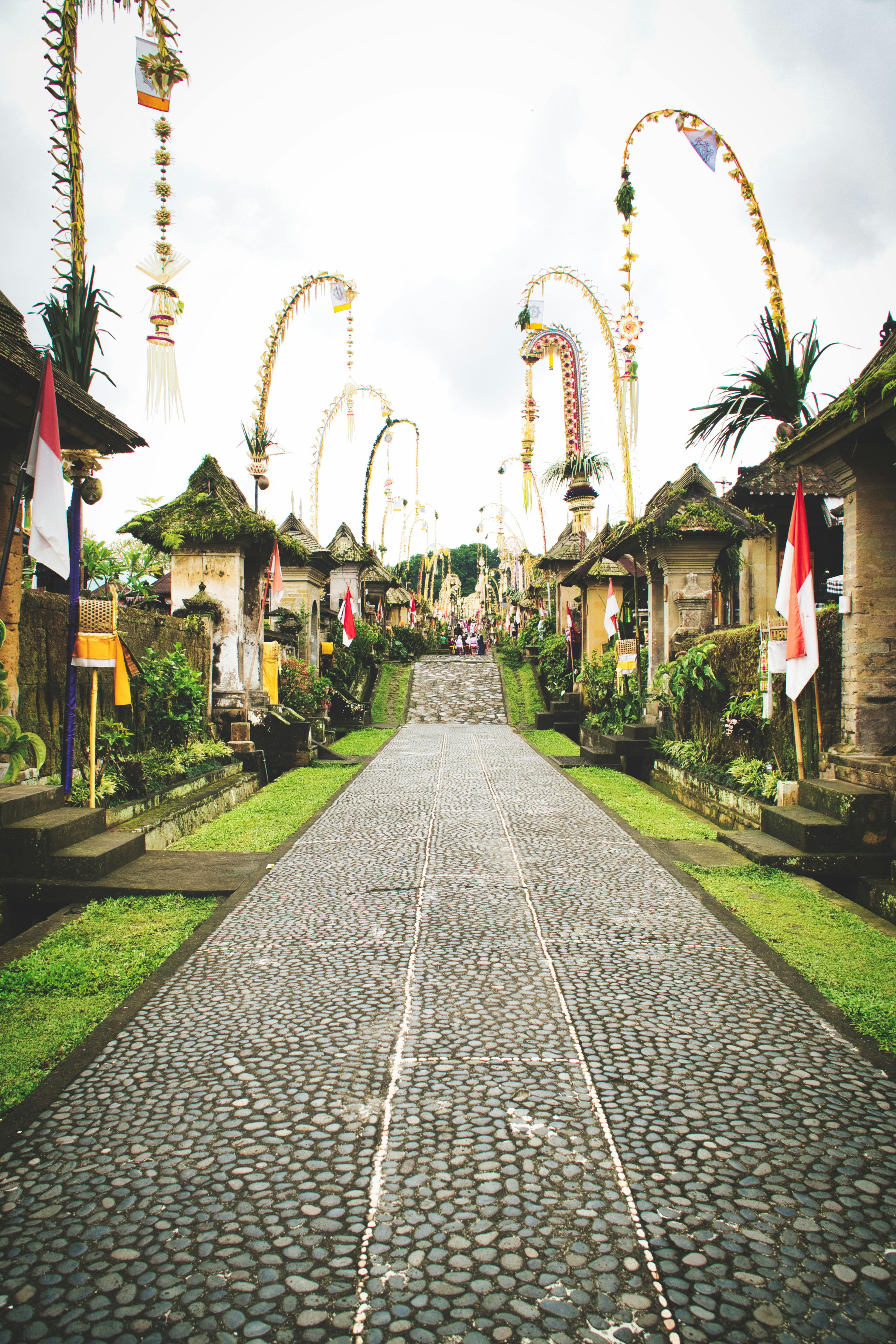 Tall penjor bamboo poles decorated with woven coconut leaves along a Bali village road during Galungan festival