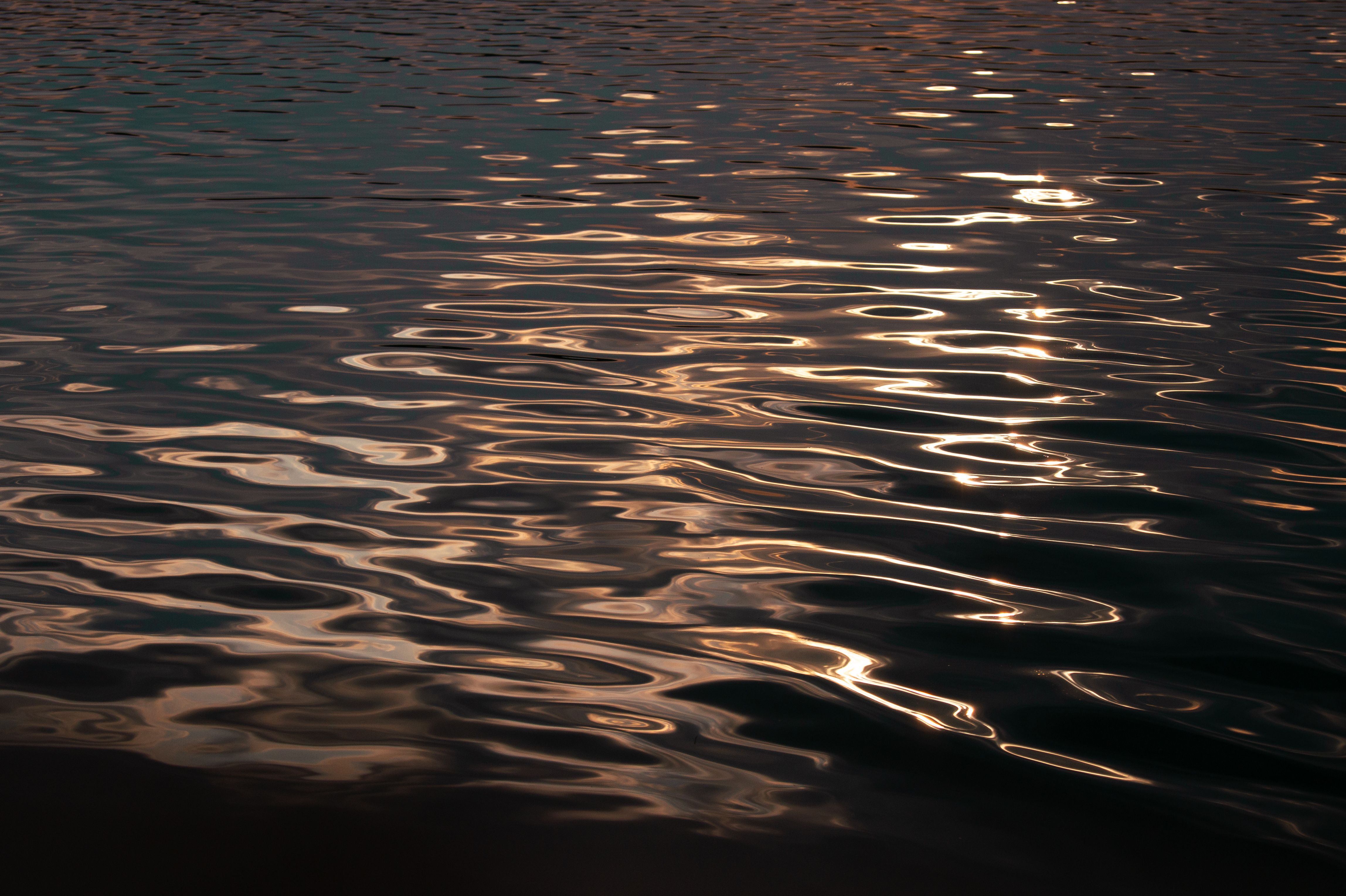 Serene Sunset Reflections on Rippling Water · Free Stock Photo