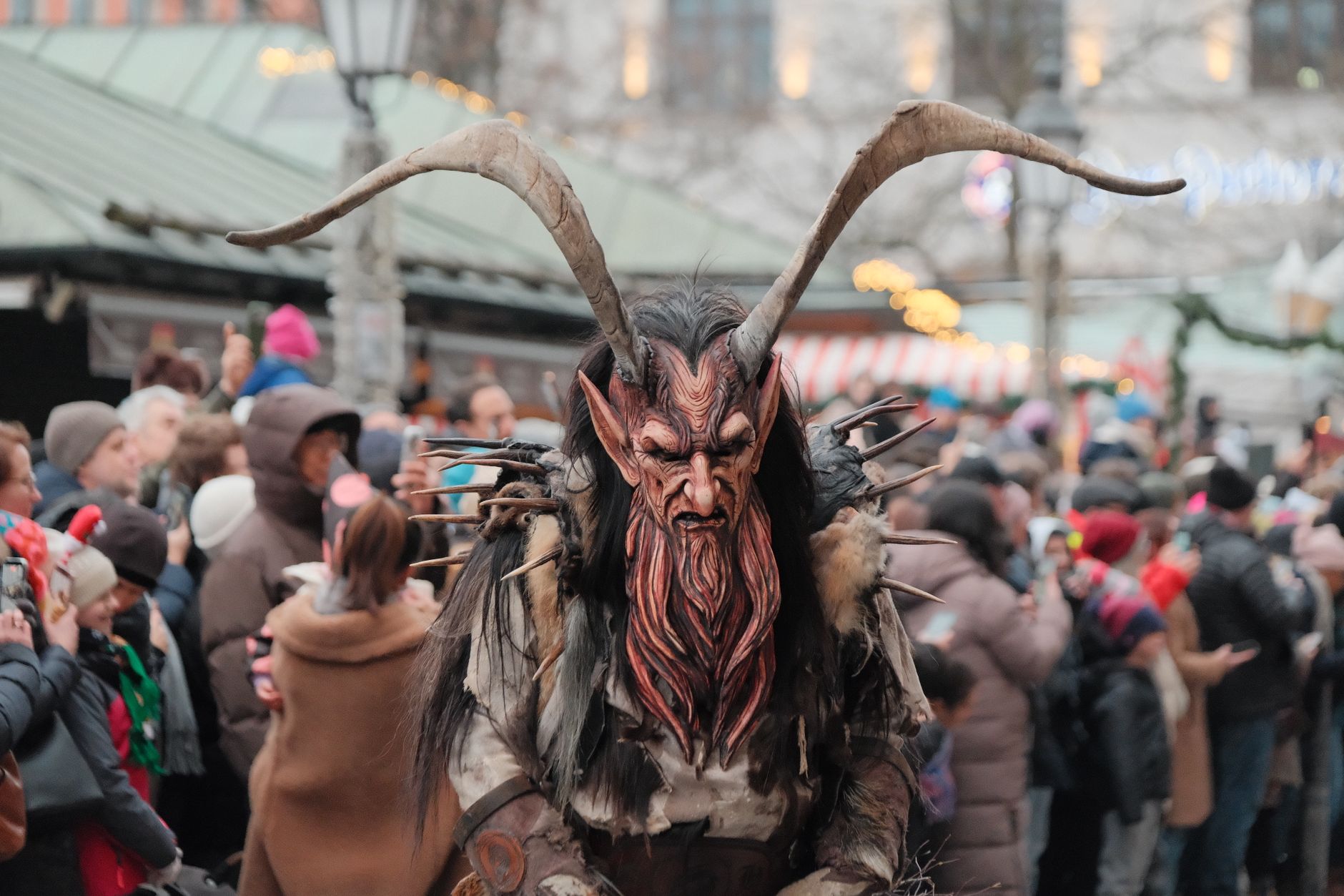 Intense Krampus figure amidst crowd at Munich's winter parade.