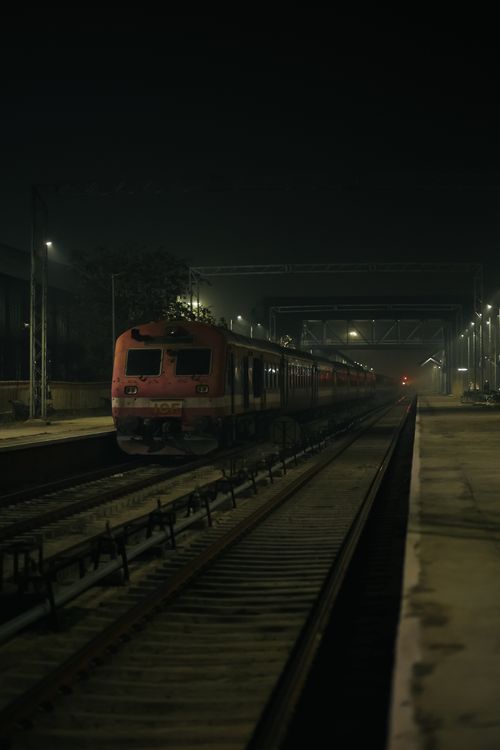 Free A train parked at a dimly lit station platform at night, evoking a quiet, mysterious mood. Stock Photo