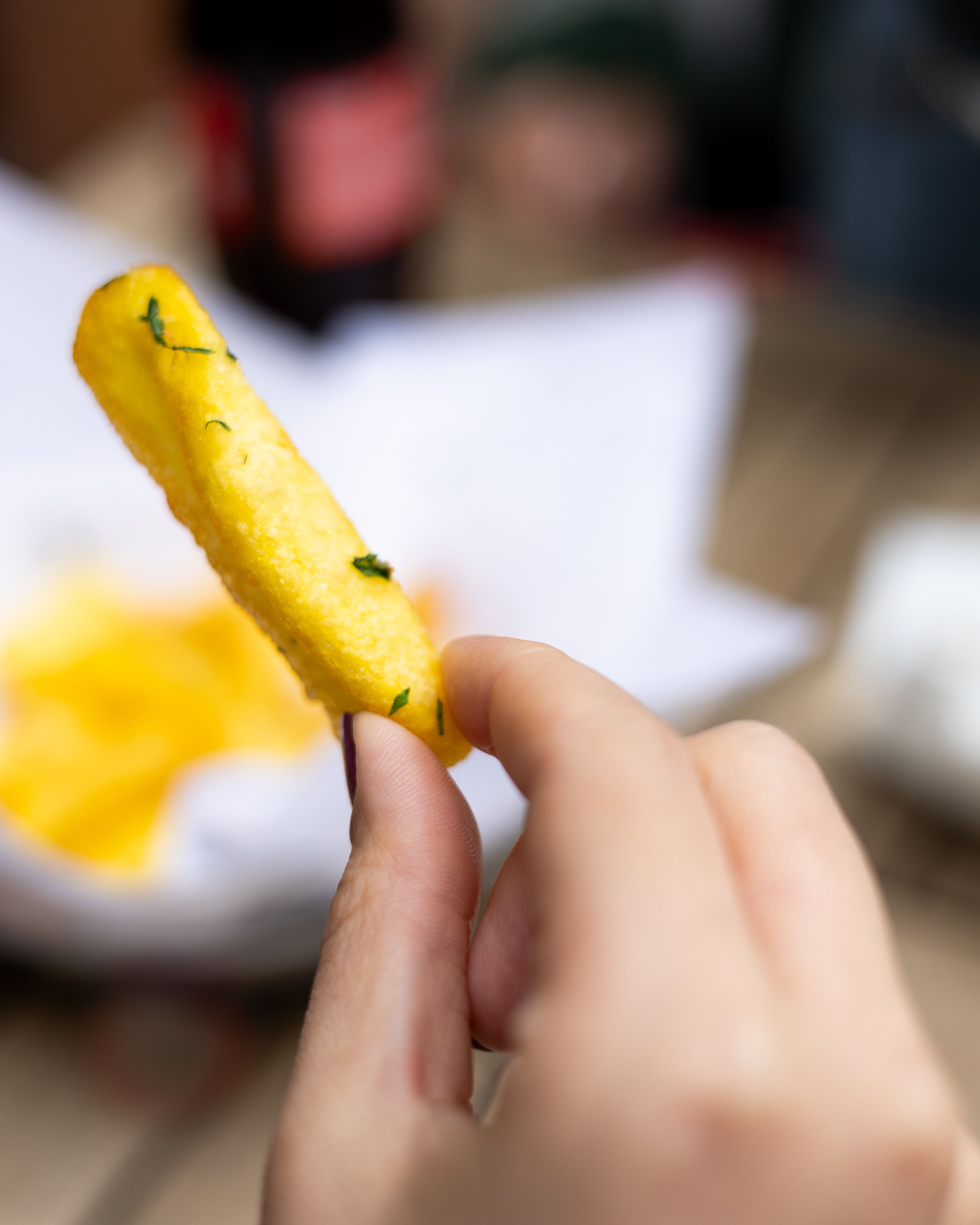 Close-up of Hand Holding a French Fry Outdoors · Free Stock Photo