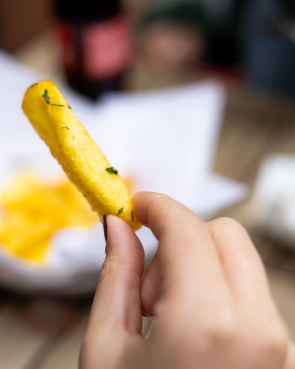 Frinch Hand Close-up of Hand Holding a French Fry Outdoors · Free Stock Photo