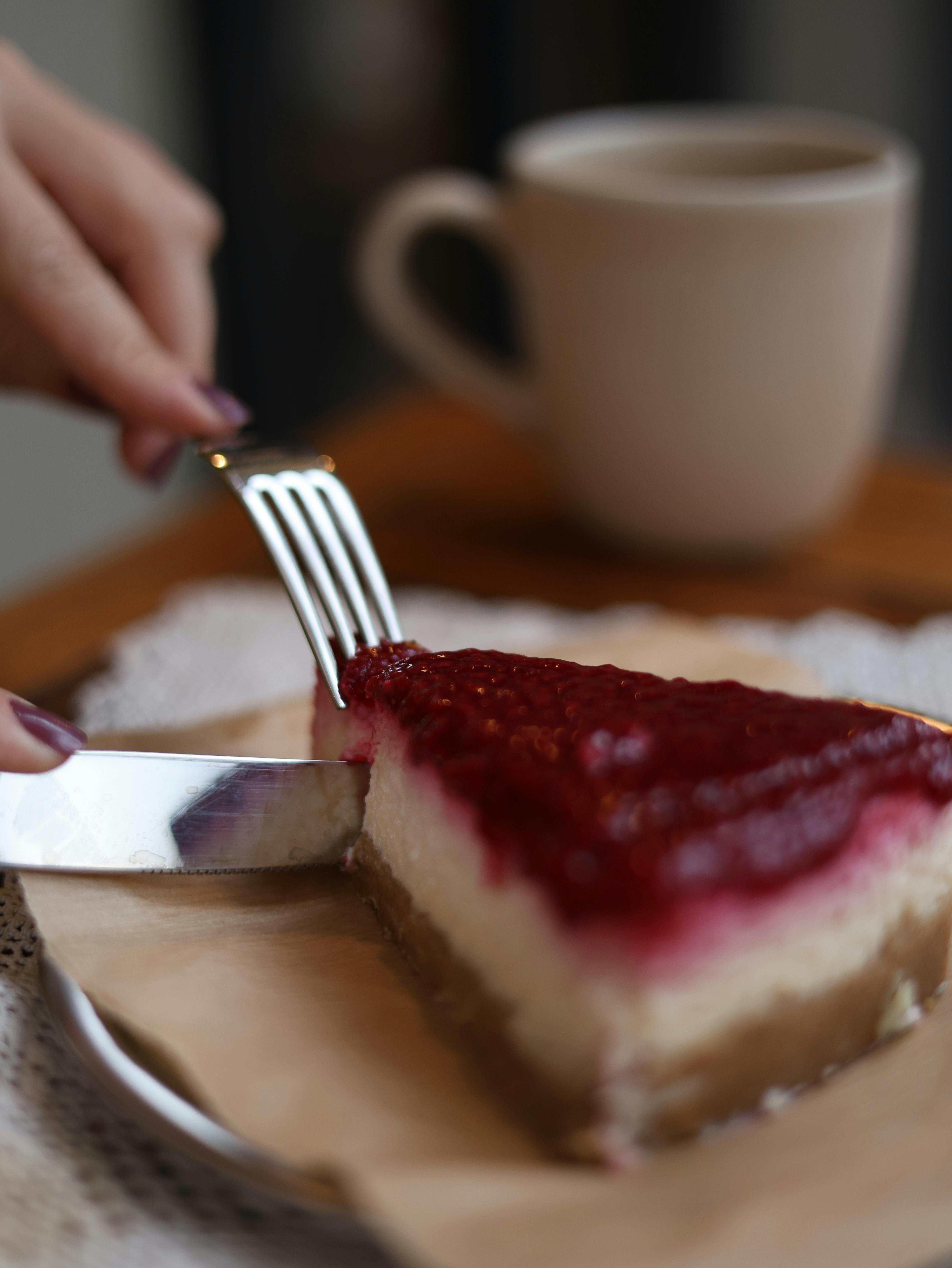 A close-up image of a berry cheesecake slice with a coffee cup in a cozy setting.
