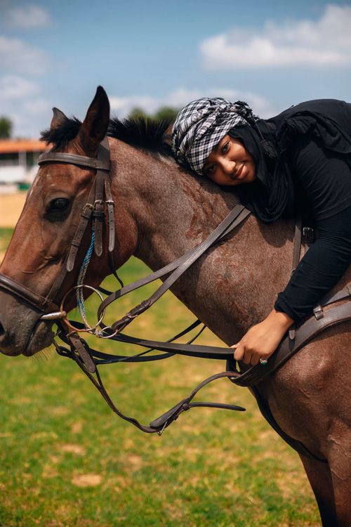 Free A smiling young woman embraces a brown horse outdoors on a sunny day. Stock Photo