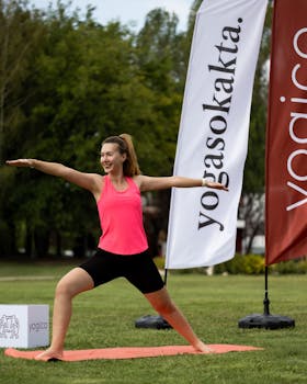 Woman practicing yoga outdoors performing warrior pose during a fitness event.
