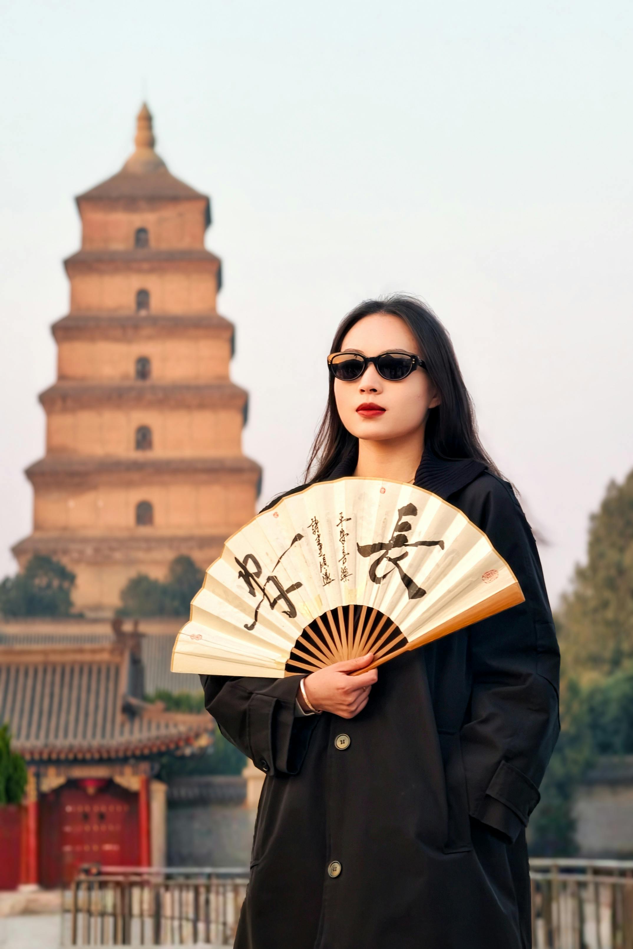 Woman holding fan in front of Giant Wild Goose Pagoda, China.