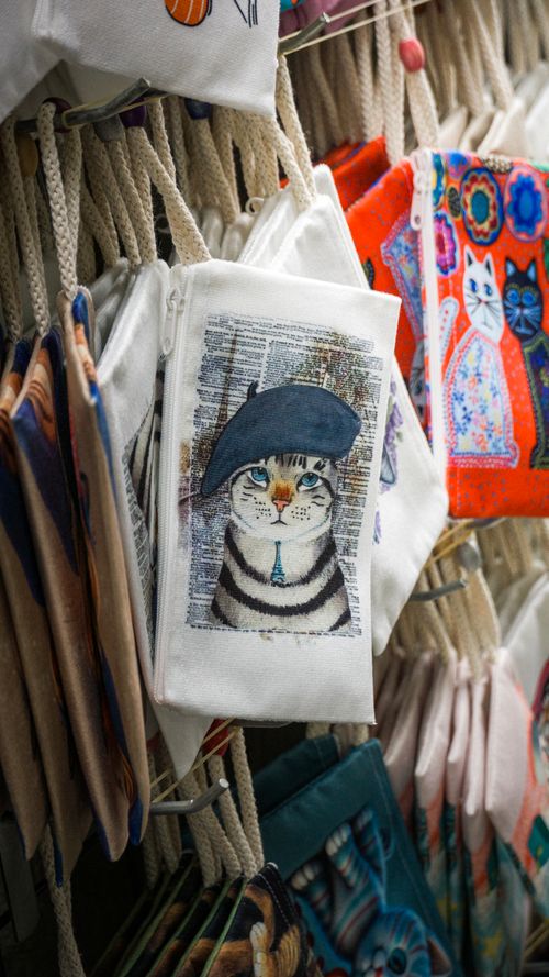Free A vibrant display of cat-themed pouches with artistic designs in a market setting. Stock Photo