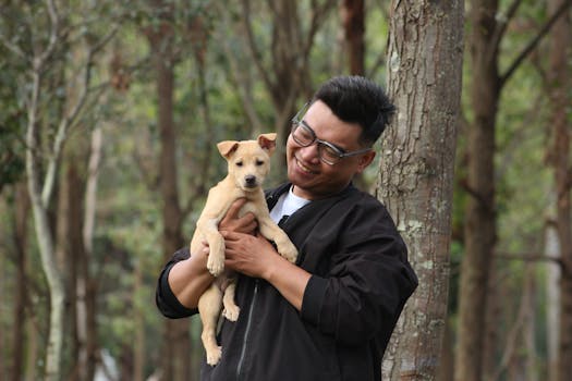 A joyful moment with a man holding a puppy in a lush forest setting.