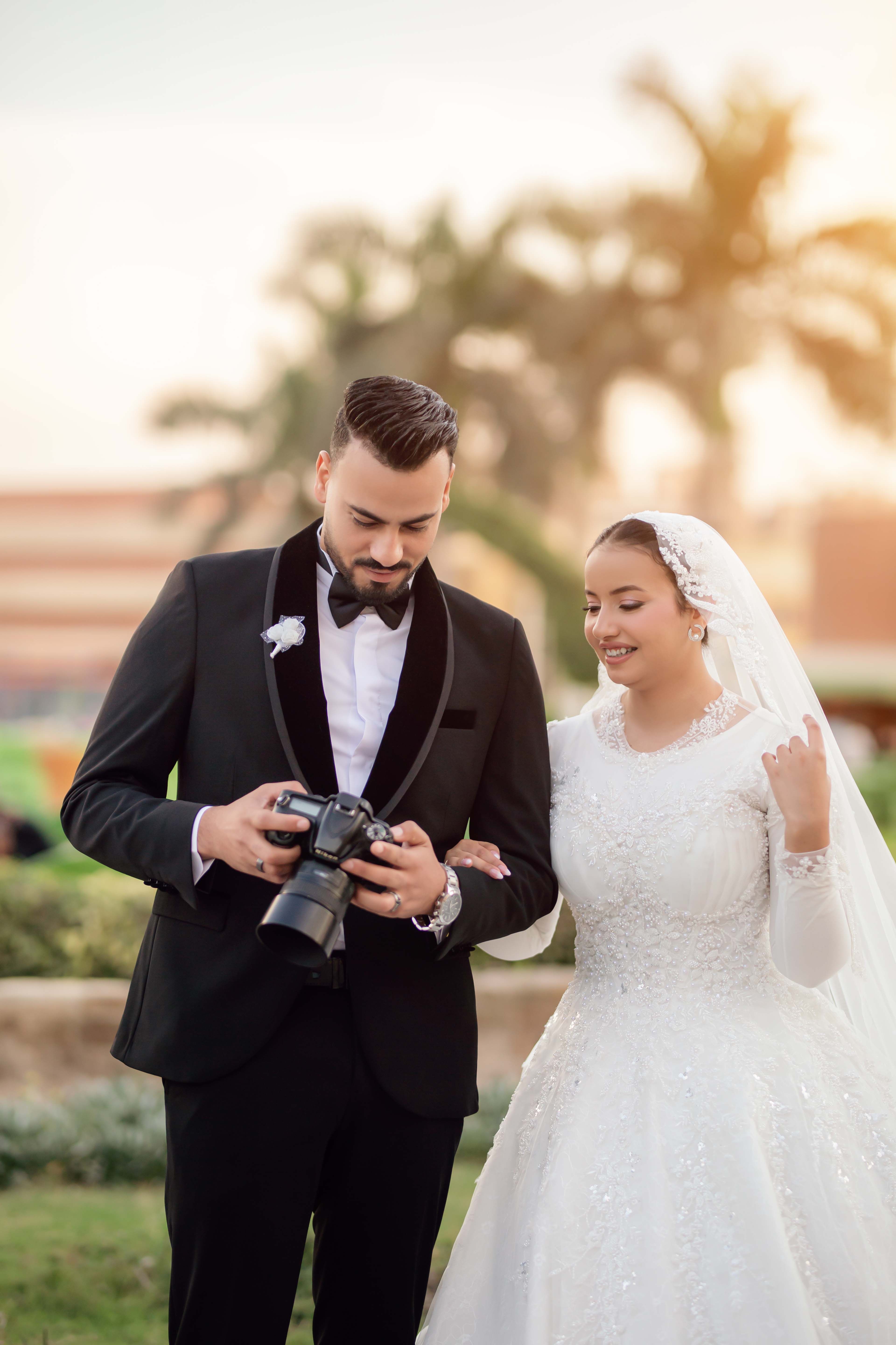 Bride and groom review photos on camera in a serene outdoor setting.