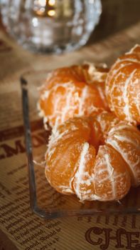 Close-up of peeled oranges on a clear glass tray, set on a text printed tablecloth.
