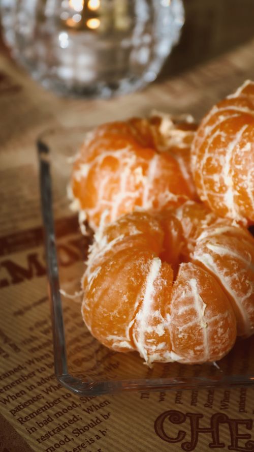 Free Close-up of peeled oranges on a clear glass tray, set on a text printed tablecloth. Stock Photo