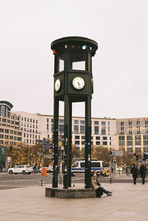 Free Street scene at Potsdamer Platz in Berlin featuring the famous clock tower and urban architecture. Stock Photo
