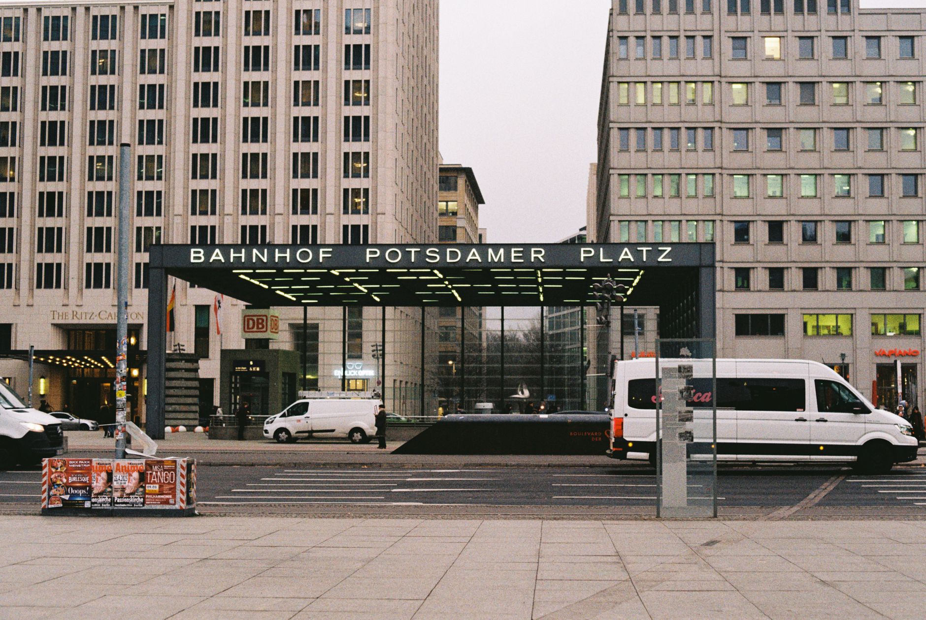 Urban scene of Bahnhof Potsdamer Platz in Berlin with visible modern architecture and vehicles.