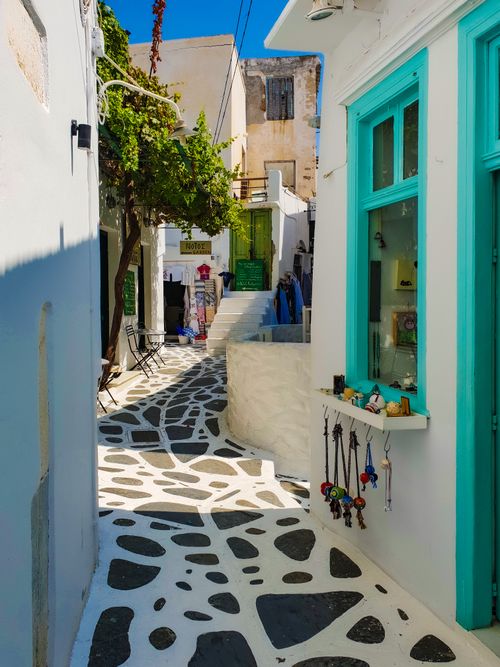 Free Picturesque street in a Greek island with white walls and blue accents, exuding a vibrant summer vibe. Stock Photo