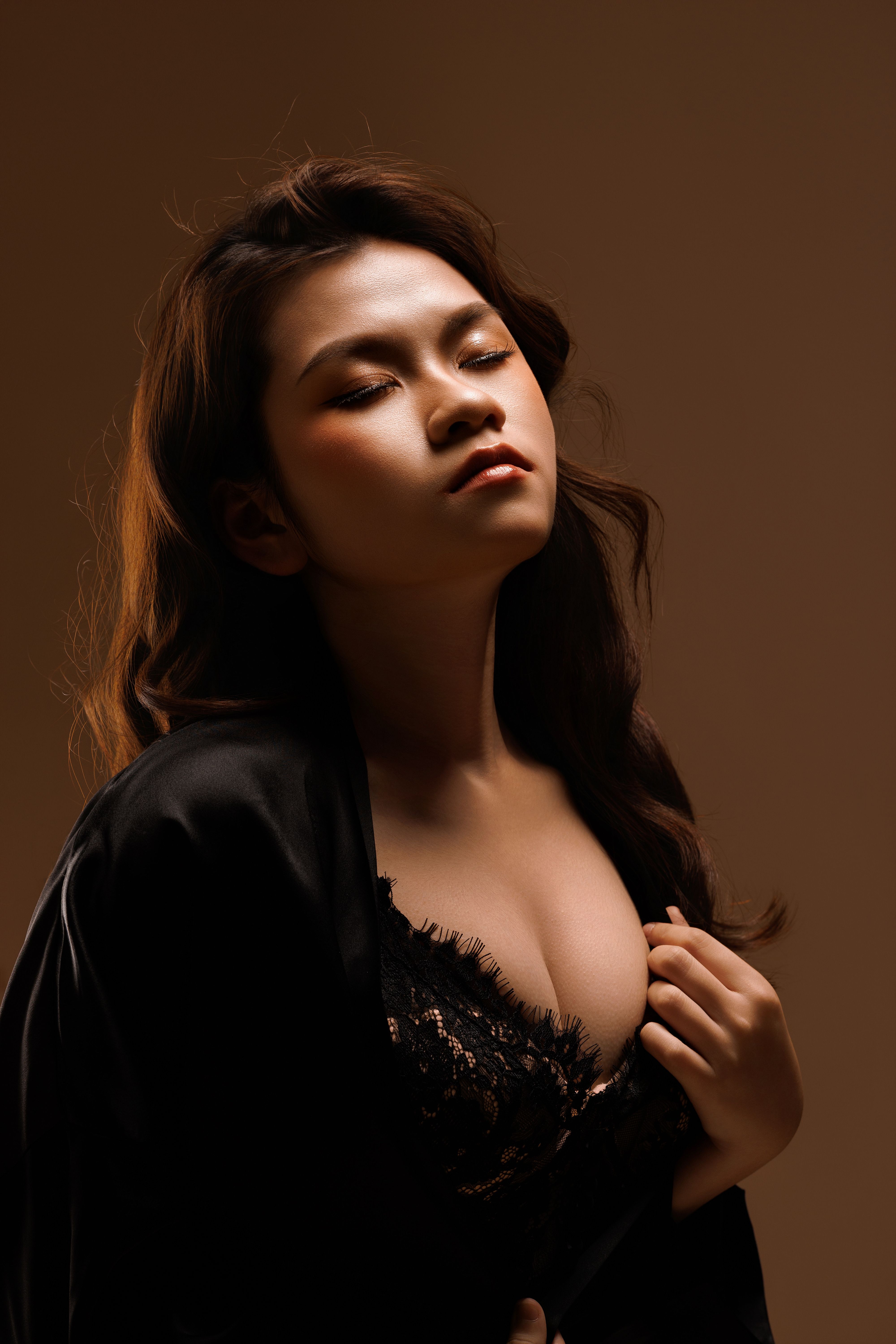 Artistic portrait of an adult Asian woman in elegant attire with soft lighting.