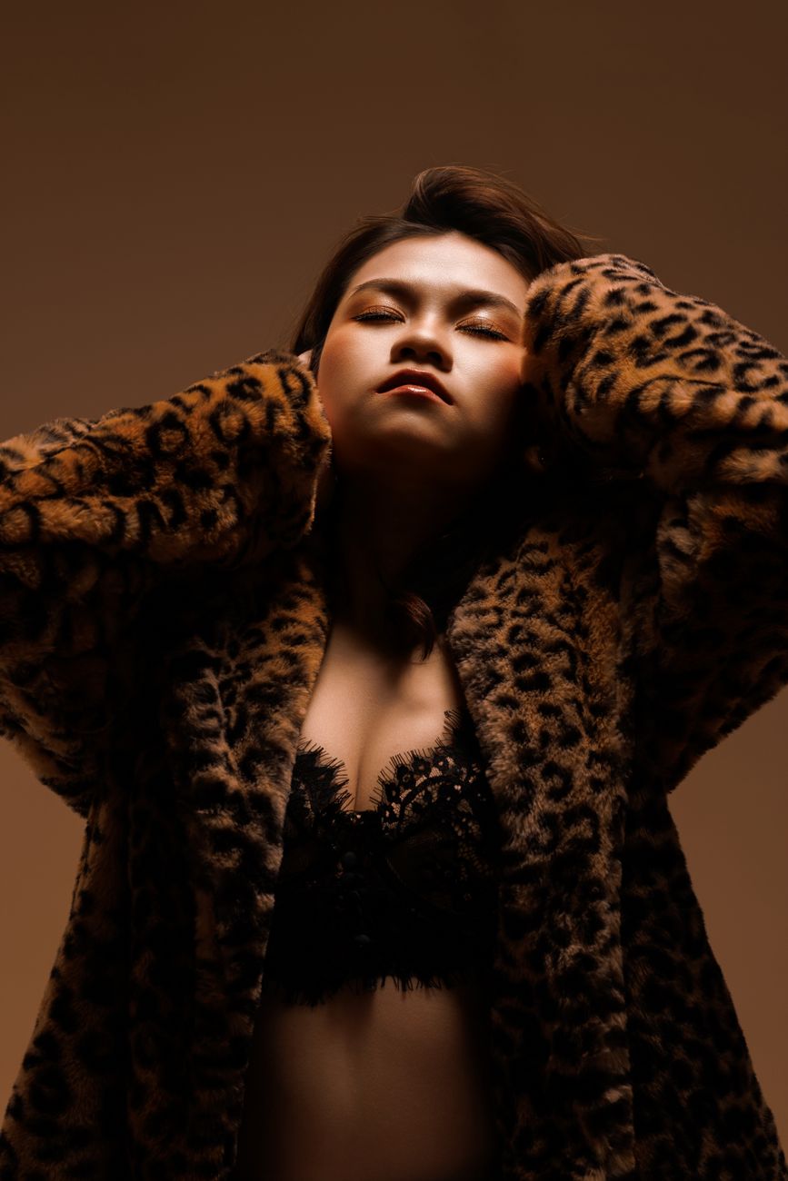 Portrait of an Asian woman in a leopard print coat, exuding confidence and style.
